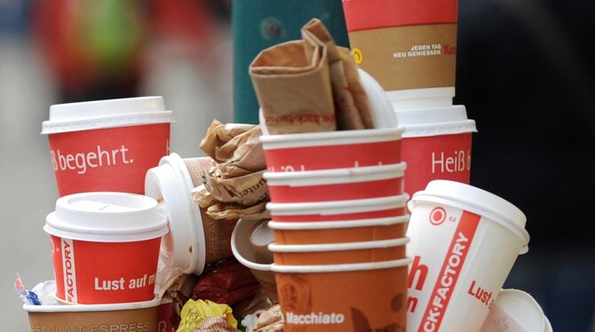 Sieht nicht schön aus und die Beseitigung ist teuer: Weggeworfene Becher stapeln sich auf einem Abfalleimer. Foto: dpa