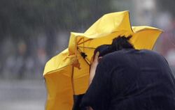Eine Frau kämpft mir einem Regenschirm gegen Windböen