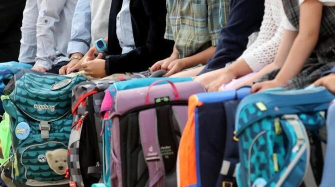 Schulkinder sitzen mit ihren Schulranzen nebeneinander