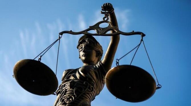 Eine Statue der Justitia hält eine Waage in ihrer Hand