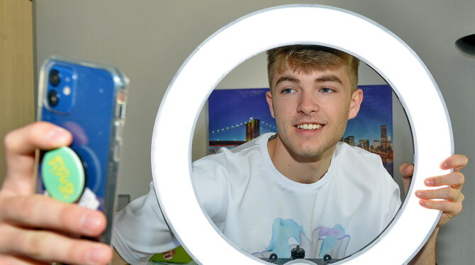 Influencer Lewinray filmt sich mit dem Handy durch ein Ringlicht.