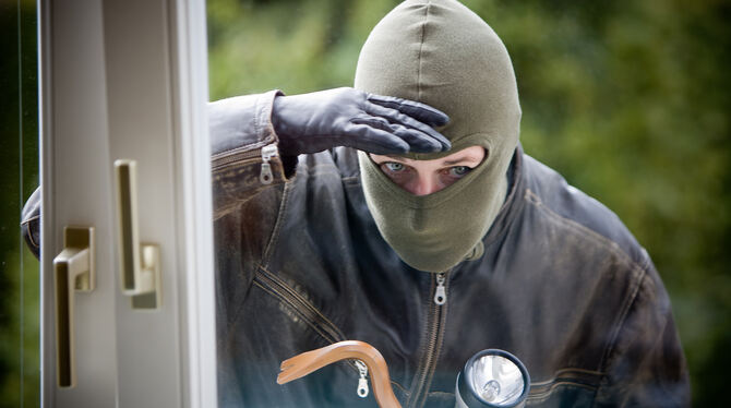 Ein Einbrecher schaut durch ein Fenster in eine Wohnung. Sechs Wohnungseinbrüche verzeichnet die Pfullinger Polizei für 2021. Vo