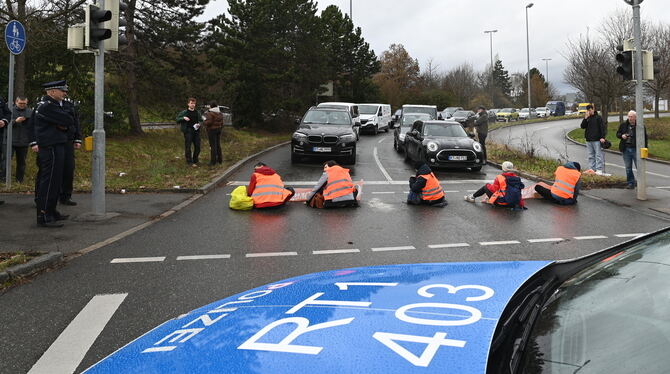 Fünf Aktivisten der »Letzten Generation«, von denen sich drei mit einer Hand an die Straße kleben, haben eine der Ausfahrten der