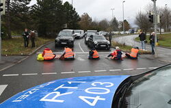 Fünf Aktivisten der »Letzten Generation«, von denen sich drei mit einer Hand an die Straße kleben, haben eine der Ausfahrten der