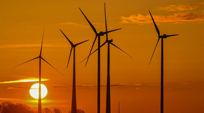 Mehrere Windräder im Sonnenuntergang.