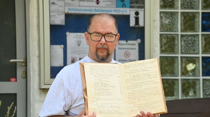 Der Vorsitzende des Schützenvereins Reicheneck, Wolfgang Tessmer, zeigt eine hand-geschriebene Vereins-Chronik. FOTO: ZENKE Der Vorsitzende des Schützenvereins Reicheneck, Wolfgang Tessmer, zeigt eine hand-geschriebene Vereins-Chronik. FOTO: ZENKE