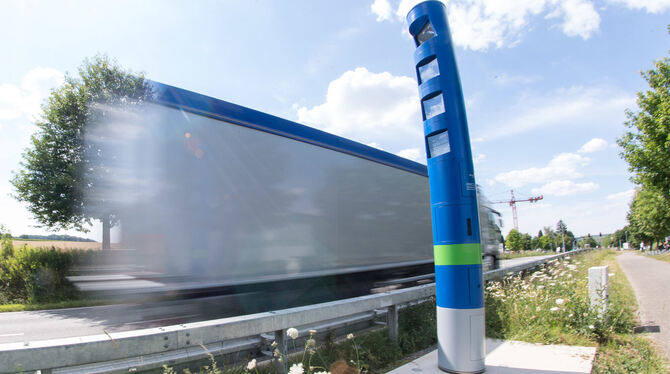 Ein Lastwagen fährt an einer Mautsäule auf einer Bundesstraße vorbei (Wischeffekt durch Langzeitbelichtung). Die Logistikbranch