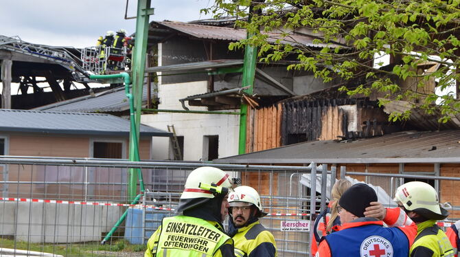 Großbrand Pferdehof Einsatzkräfte am Samstag vor der Brandruine, wo die Drehleiterbesatzung ein aufgelodertes Feuer bekämpft.
