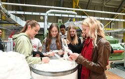 Gymnasiasten in der Maschinenhalle der Hochschule Reutlingen: Von Hand zu Hand wandern Baumwollflocken, dann die dickeren Karden