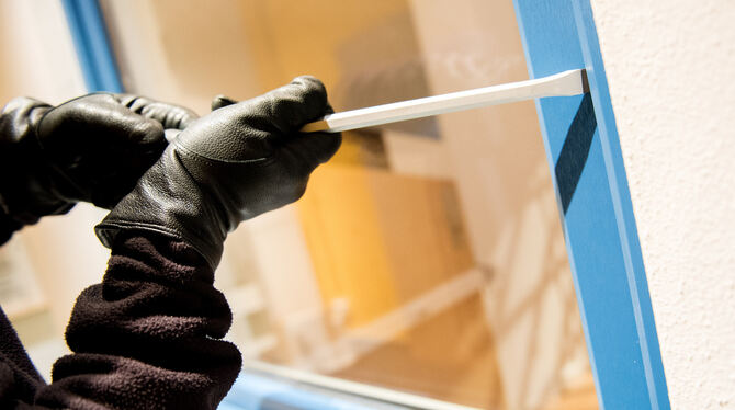 Ein Einbrecher auf Beutezug versucht mit einem Schraubenzieher ein Fenster aufzuhebeln.
