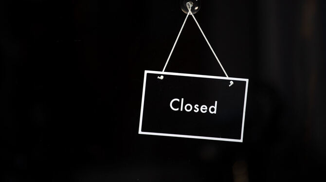 Ein Schild mit der Aufschrift »Closed« hängt an einer Ladentür.