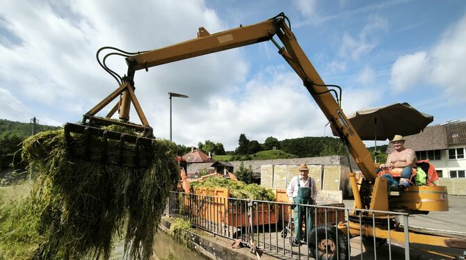 Bernd »Beba« Geiger vom Uracher Bauhof holt die abgemähten Wasserpflanzen mit einer Greifzange aus der Erms. An seiner Seite der