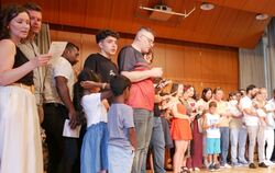 Gemeinsam mit Landrat Dr. Ulrich Fiedler (rechts) sangen die Eingebürgerten am Dienstag die deutsche Nationalhymne auf der Bühne