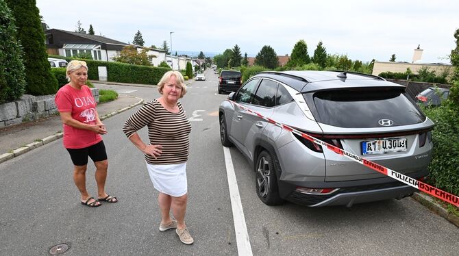 Uta Ellwanger (links) steht im Königssträßle neben ihrem geparkten Auto, das ein Raser kaputt gemacht hat. Gemeinsam mit Nachbar
