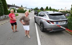 Uta Ellwanger (links) steht im Königssträßle neben ihrem geparkten Auto, das ein Raser kaputt gemacht hat. Gemeinsam mit Nachbar