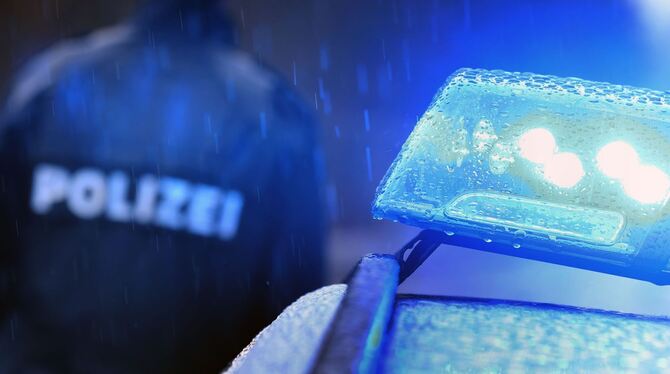 Justiz,Kriminalität,Polizei,lby,bay Ein Polizist steht an einem Streifenwagen, an dem das Blaulicht leuchtet.