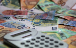 Ein Taschenrechner liegt auf verschiedenen Euro-Banknoten. 