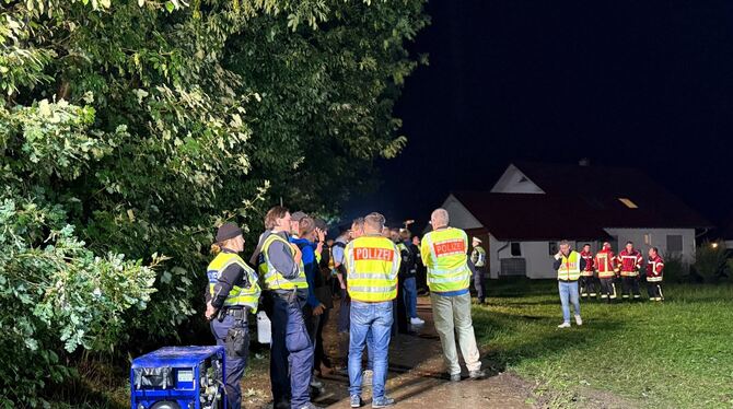 Einsatzkräfte stehen nahe des entgleisten Personenzuges an einem Streckenabschnitt.