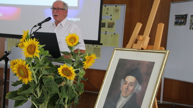 Dettingen Homöopathie Jubiläum Vorsitzender Dieter Sigler bei seiner Festred. Im Vordergrund ein Bild von Samuel Hahnemann, dem Begründer der Homöopathe.