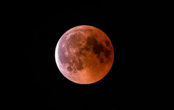 Der teilweise vom Erdschatten verdunkelte Vollmond leuchtet während einer Mondfinsternis rötlich.