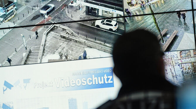 Ein Beamter im Führungs- und Lagezentrum des Polizeipräsidiums Mannheim vor einer Wand mit Bildschirmen. Das Land Baden-Württemb