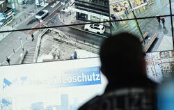 Ein Beamter im Führungs- und Lagezentrum des Polizeipräsidiums Mannheim vor einer Wand mit Bildschirmen. Das Land Baden-Württemb