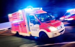 Rettungswagen der Feuerwehr fährt mit Blaulicht durch eine Straße