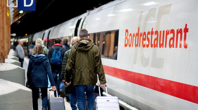 Fahrgäste gehen am frühen Morgen mit ihrem Gepäck über einen Bahnsteig, um in einen ICE der Deutschen Bahn (DB) einzusteigen.