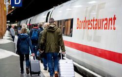 Fahrgäste gehen am frühen Morgen mit ihrem Gepäck über einen Bahnsteig, um in einen ICE der Deutschen Bahn (DB) einzusteigen.