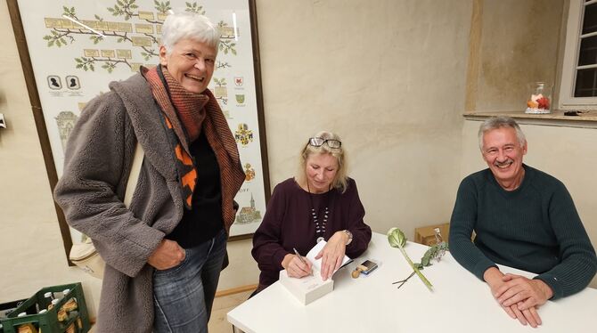Lesung Birgit Juvesa Die Kirchentellinsfurter Autorin Birgit Juresa (Mitte) signiert im Beisein ihres Ehemannes Ivi ihr Buch »Bürotope« für eine Besu