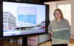Tanja Niederfeld zeigt ihren Holzschnitt vor einer Präsentation der Fassade, auf die er übertragen wurde.